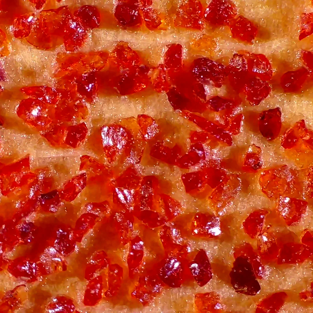 Magnified view of 50 grit garnet sandpaper, showing red garnet crysals over a glued backing